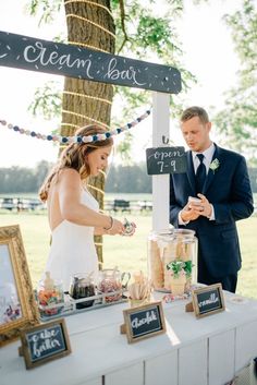 a man and woman standing at a table in front of a sign