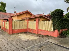 an orange house with a yellow fence in front of it