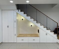 an empty room with white cabinets under the stair case and storage units below it on either side of the stairs