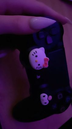 a person holding a remote control with hello kitty stickers on it's side