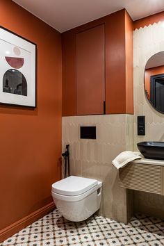 a bathroom with a toilet, sink and mirror on the wall next to a tiled floor