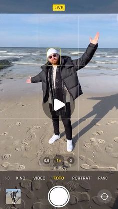 a man standing on top of a sandy beach next to the ocean with his hands in the air