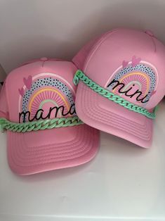 two pink hats with the word mama written on them, sitting next to each other