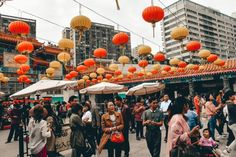 many people are walking around with umbrellas and lanterns hanging from the ceiling above them