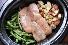 two pieces of chicken, green beans and apples in a crock pot with seasoning