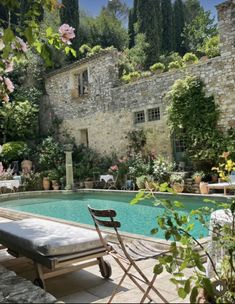 an outdoor pool surrounded by greenery and stone walls, with chairs around the edge