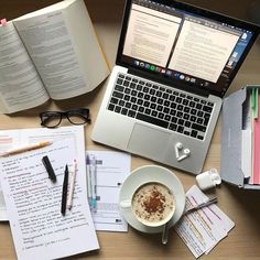 an open laptop computer sitting on top of a desk next to a cup of coffee