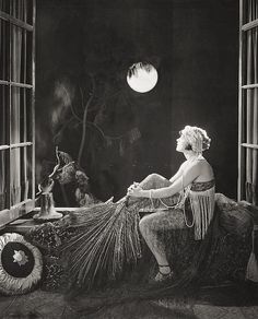 a black and white photo of a woman sitting on a couch in front of a window