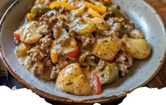 a white plate topped with meat and veggies covered in gravy on top of a wooden table