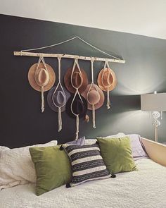 a bed with hats hanging on the wall above it and two lamps next to it