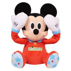 a mickey mouse stuffed animal sitting on top of a white surface with its hands up to his ears