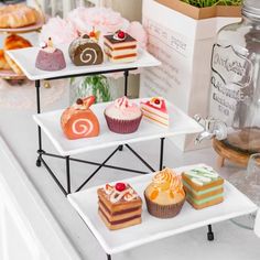 three tiered trays filled with cakes and cupcakes on top of a counter