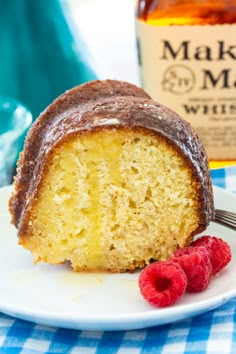 a piece of cake on a plate with raspberries and a bottle of maple syrup