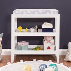 a baby's room with blue walls, white furniture and toys on the floor