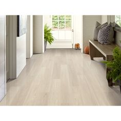 a living room filled with lots of furniture and plants on top of wooden flooring