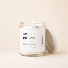 a white candle with the words love you mom printed on it next to an empty jar