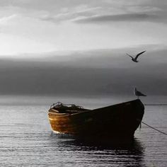 a boat floating on top of a body of water under a sky filled with clouds