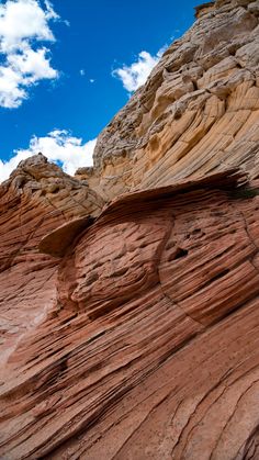 a rock formation in the desert under a blue sky with some white clouds above it