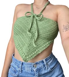 a woman wearing a green crop top with a tie around her neck and tattoos on her arm