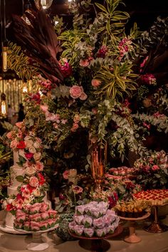 a table topped with lots of different types of cakes and flowers on top of it