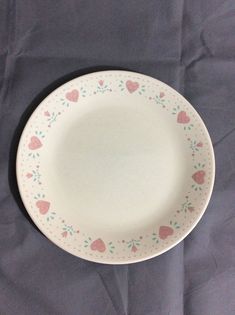 a white plate with pink hearts on it sitting on a blue tableclothed surface