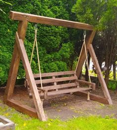 a wooden swing set in front of some trees