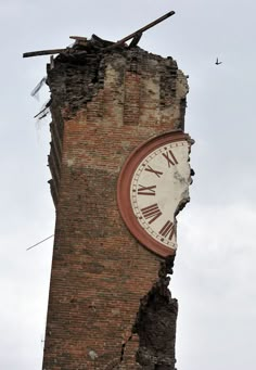 a clock that is on the side of a brick building with torn up walls and debris