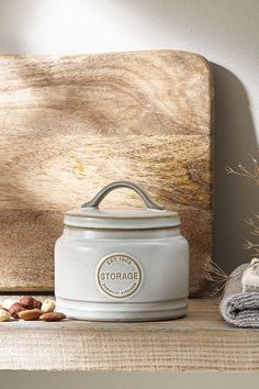 a white canister sitting on top of a wooden shelf