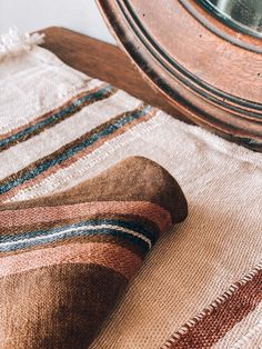 a close up of a striped rug with a clock in the back ground and a mirror behind it