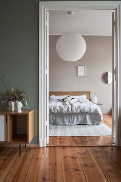 an open door leading to a bedroom with a bed and nightstand in the middle of it