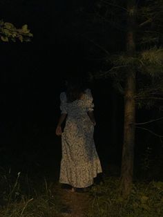 a woman is walking through the woods at night