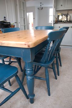 a kitchen table with blue chairs and a wooden top in the middle of an open floor plan