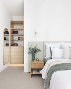 a bedroom with white walls and carpeted flooring has a bed, nightstands, and open shelving unit