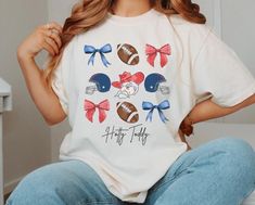 a woman sitting on top of a bed wearing a shirt with footballs and bows