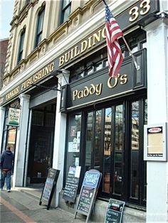 the building has an american flag hanging from it's front window and signs outside