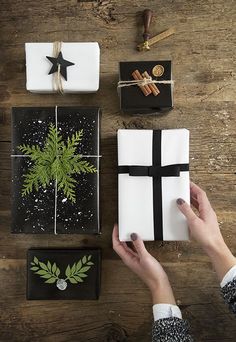 a person holding a present box with a tree on it and other gifts around it