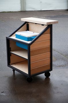 a small cart with drawers on wheels in the middle of a parking lot next to a garage