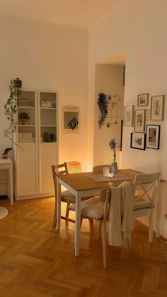 a dining room table with chairs and pictures on the wall