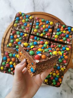 a person holding a piece of cake with chocolate and candy on it