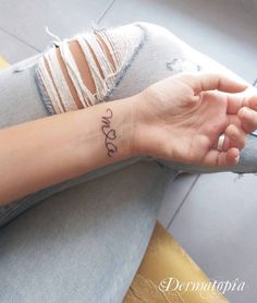 a woman's arm with the word love tattooed on her left wrist, in black ink