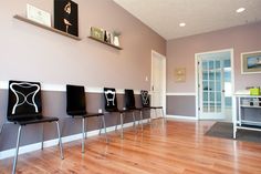 a row of chairs sitting on top of a hard wood floor next to a wall