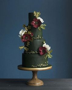 a three tiered green cake with flowers on the side and gold trimmings