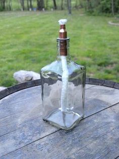 an empty glass bottle sitting on top of a wooden barrel