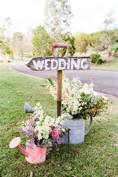 an old watering can with flowers and a sign that says wedding