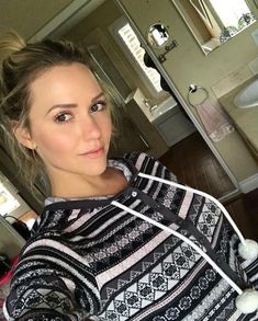 a woman is taking a selfie in the bathroom with her hair pulled back and wearing a sweater