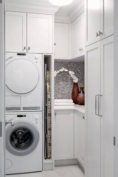 a white washer and dryer in a small room next to some cupboards