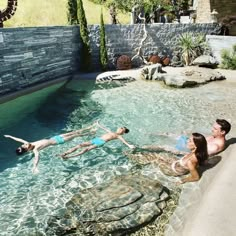 two people are swimming in a pool with rocks