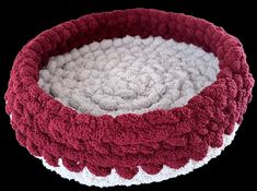 a red and white crochet basket with yarn in it on a black background