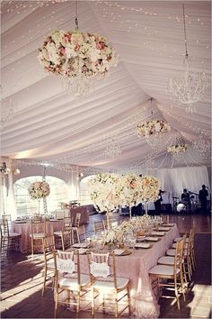 an image of a wedding tent with flowers on the table and chandeliers hanging from the ceiling