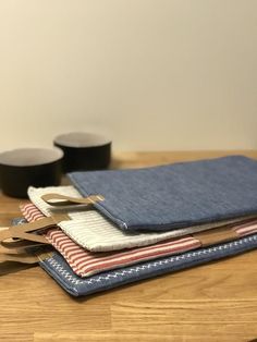 a stack of cloths and scissors sitting on top of a wooden table next to two black bowls